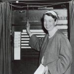 Black and white photo of Eleanor Roosevelt with a voting machine